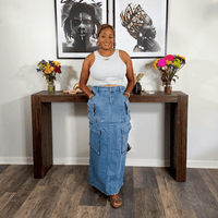 Woman standing behind a wooden console table with decorative items in a room.