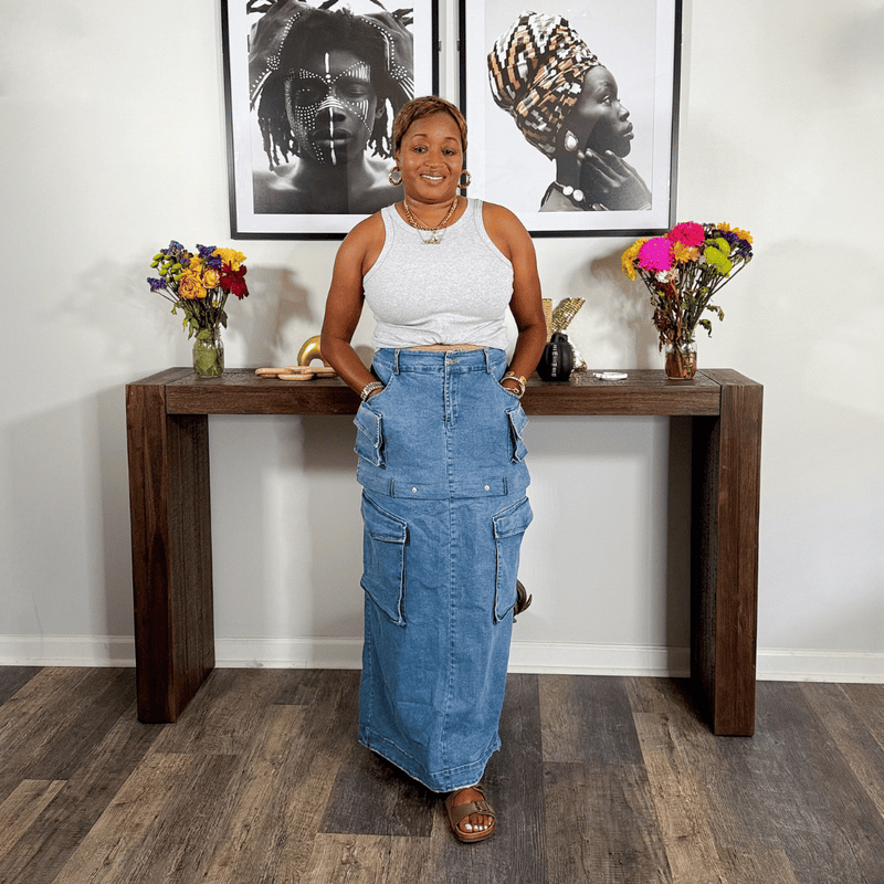 Woman standing behind a wooden console table with decorative items in a room.