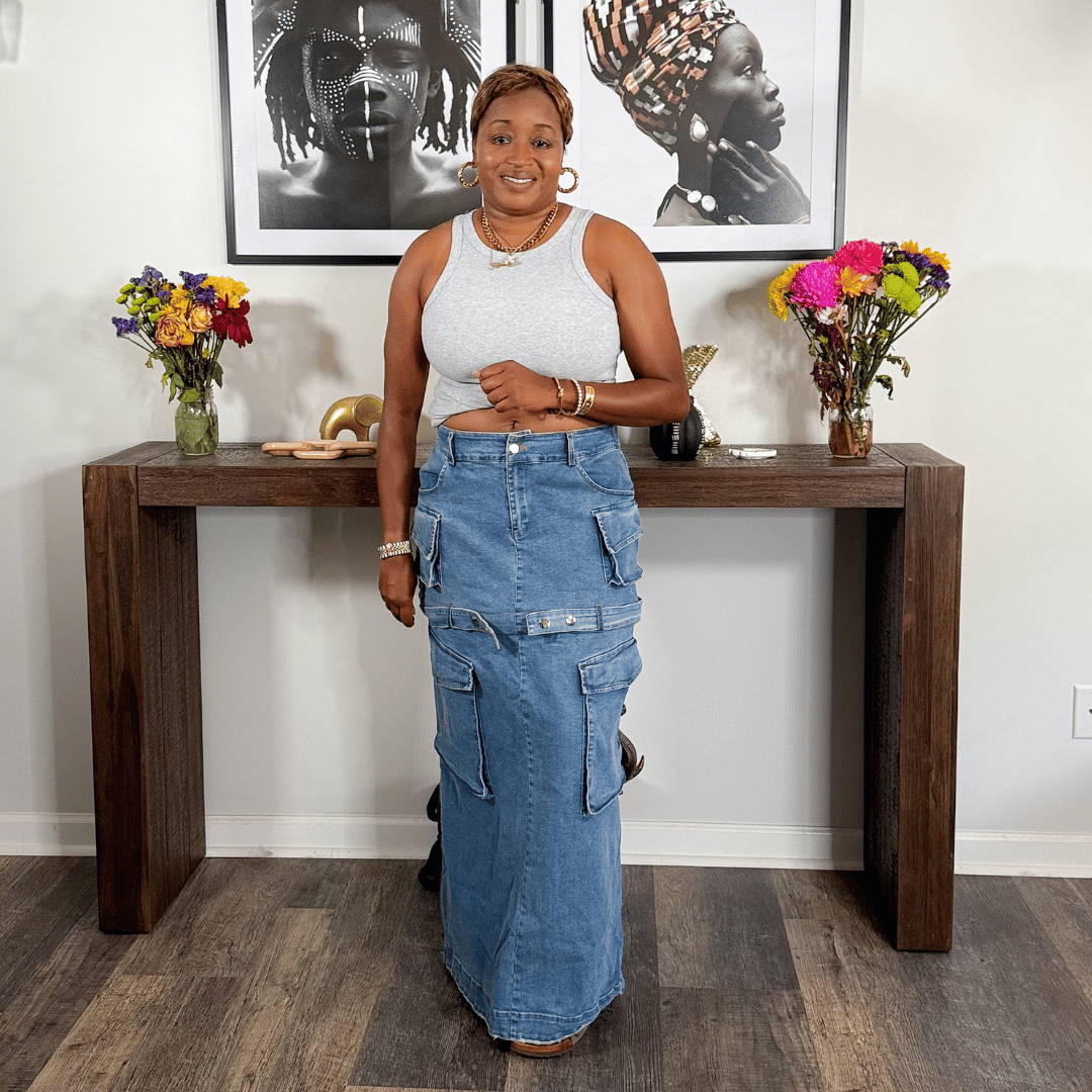 Woman standing in a room with a wooden console table, flowers, and framed art on the wall.