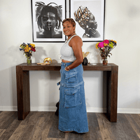 Woman standing in a room with a wooden console table, flowers, and framed art on the wall.
