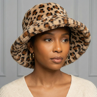 African American woman wearing a tan leopard faux fur bucket hat with a soft plush texture, styled low for a chic boutique look.
