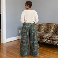 Back view of oversized camouflage wide-leg denim gauchos, showcasing a relaxed fit and elastic waistband, on an African American model.