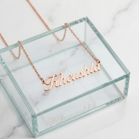 Rose gold cursive personalized name necklace spelling Kheushla on a glass jewelry box