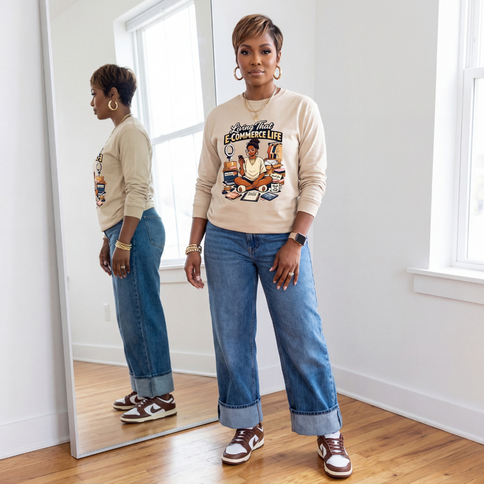 Woman standing in front of a mirror wearing a graphic sweatshirt and jeans.
