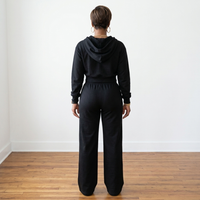 Back view of the black Tana Hooded Track Suit, showing the hood resting on the upper back and pants falling over the heels.