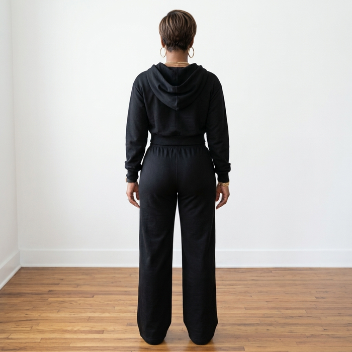 Back view of the black Tana Hooded Track Suit, showing the hood resting on the upper back and pants falling over the heels.