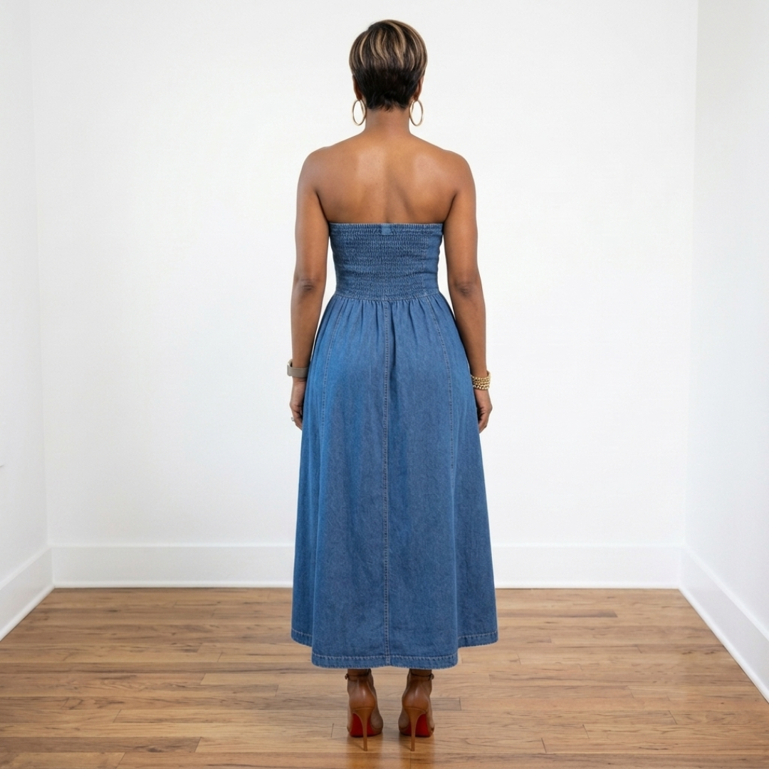 Back view of an African American woman wearing the Desi medium-wash strapless denim tube dress with a smocked back and brown Christian Louboutin Fanny sandals.