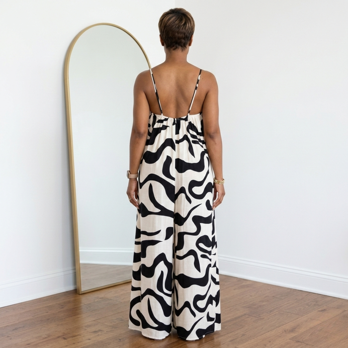Back view of black and white wide leg jumpsuit with spaghetti straps and ultra wide legs, floor-grazing length.