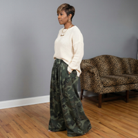 Side view of camouflage wide leg denim gauchos with elastic waistband styled with a cream sweater on an African American model.