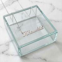 Silver cursive personalized name necklace spelling Kheushla displayed on a glass jewelry box on white marble
