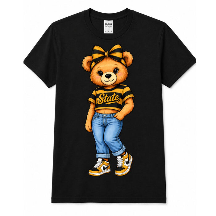 A black short-sleeve crewneck t-shirt featuring a cartoon graphic of a brown teddy bear wearing a yellow and black striped crop top with 'State' written on it, blue jeans, and yellow-and-black sneakers, displayed on a clean white background.