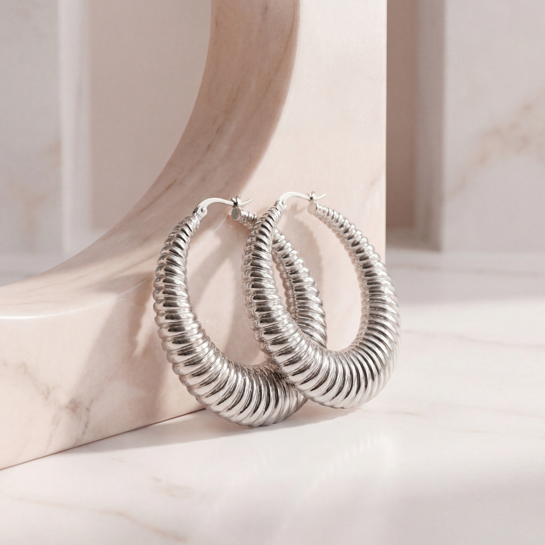 Medium 40mm silver textured hoop earrings with a modern hammered texture, polished everyday-to-statement hoops on a neutral blush background.