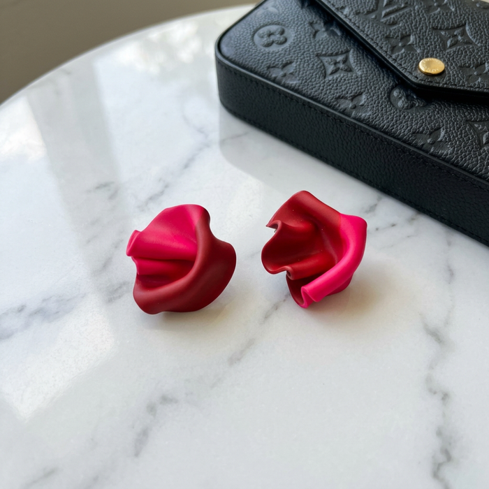 Red earrings on a marble surface with a blackLouis Vuitton box in the background