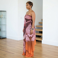 Woman wearing a strapless dress with pink and orange floral pattern in an indoor setting.