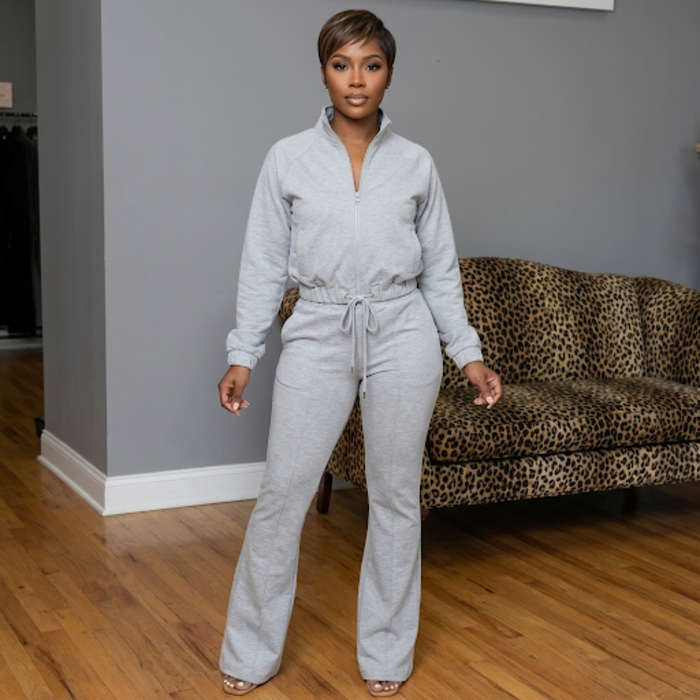 African American model wearing the Lacey Knit Track Suit in coffee, featuring a mock neck zip jacket with welt pockets and drawstring hem, paired with flared knit pants with an elastic waistband, drawstrings, side pockets, and a 33-inch inseam.