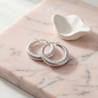 Small 33mm silver textured hoop earrings featuring a lightly hammered design, minimalist everyday hoops on a blush stone background.