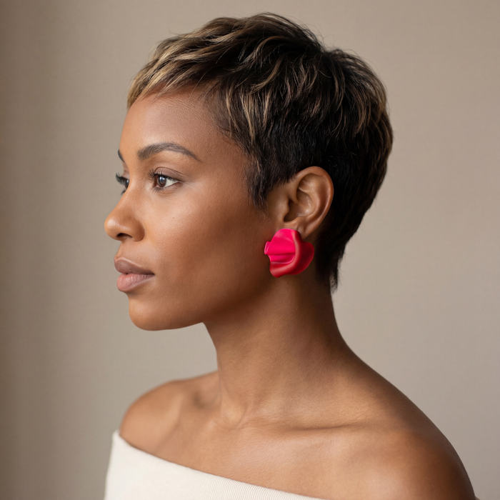 Woman with a stylish haircut and bright pink earrings against a neutral background