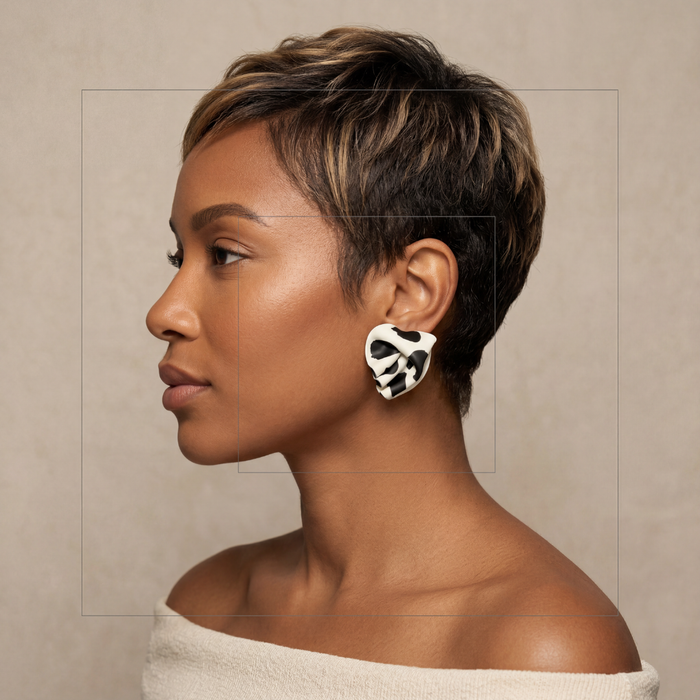 Woman with a stylish haircut and earrings against a neutral background