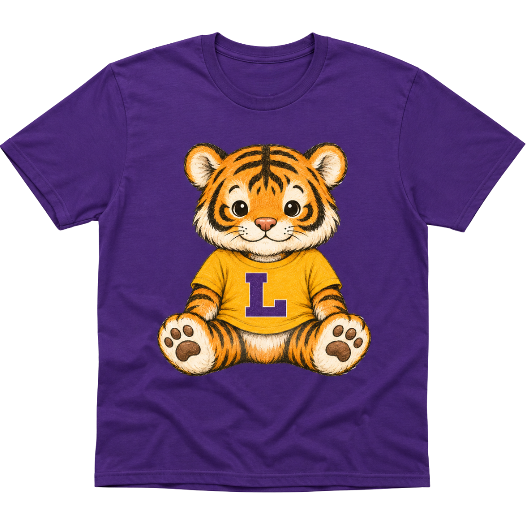 A purple short-sleeve crewneck t-shirt featuring a cartoon graphic of a smiling tiger cub wearing a yellow shirt with a purple letter 'L' on the chest, set against a plain white background.